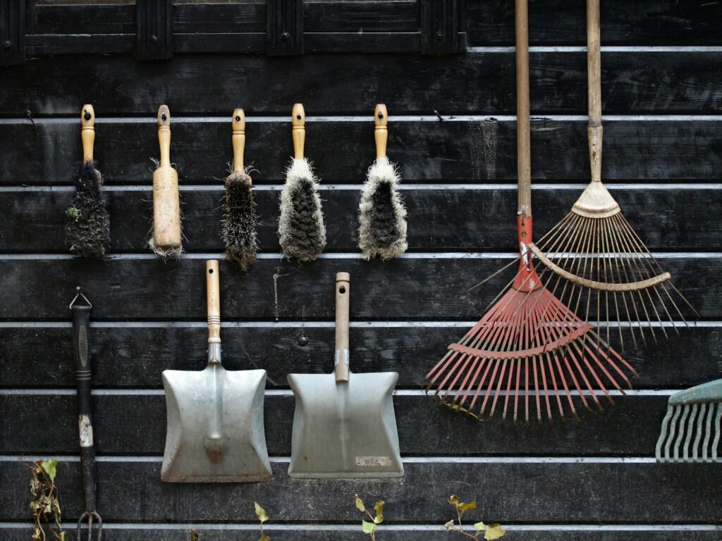 Neatly arranged garden tools hanging on a rustic wooden wall.